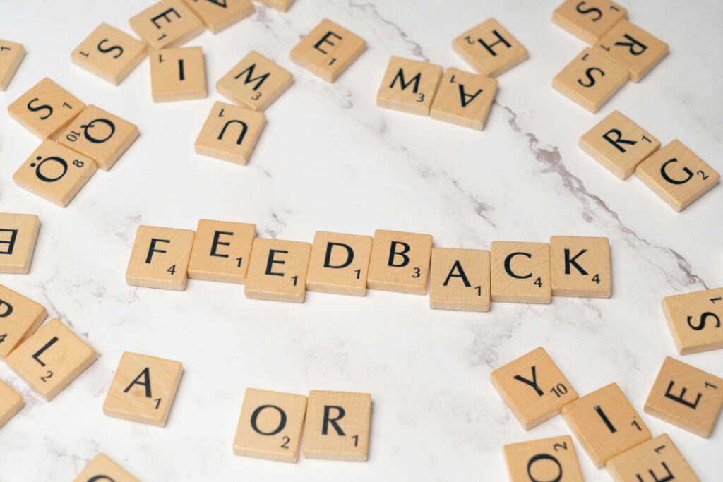 Wooden Scrabble tiles arranged to spell 'Feedback' on a marble background.