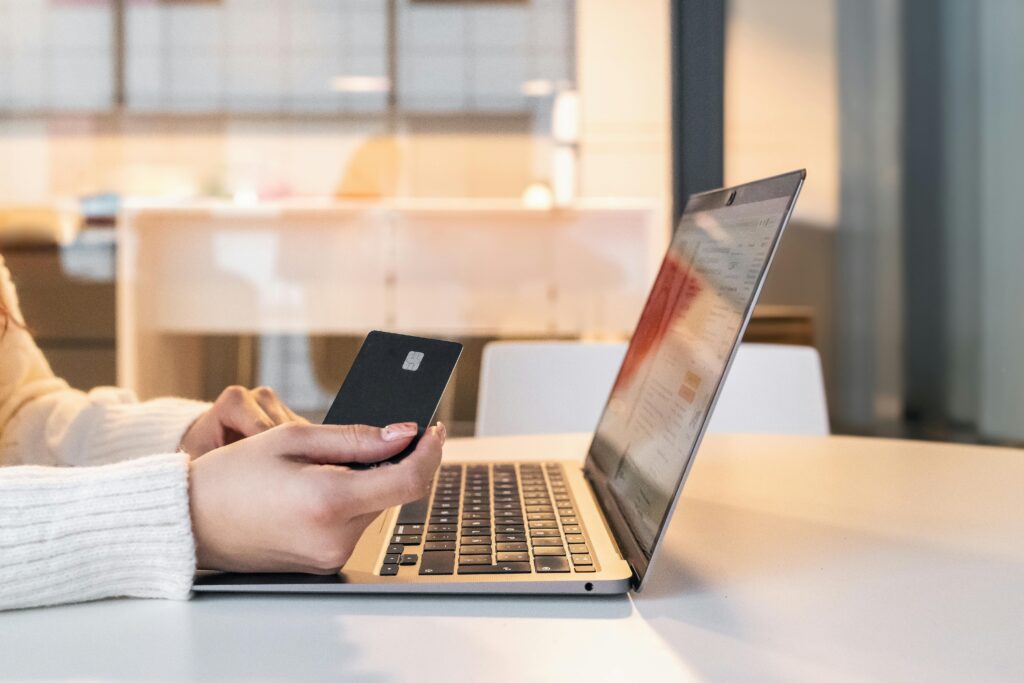 A woman using a credit card and laptop for online shopping in a modern indoor setting.